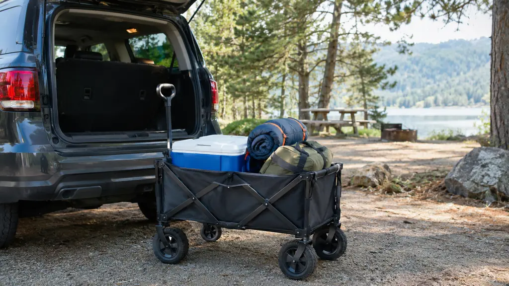 A loaded collapsible wagon with a cooler and a sleeping bag folded flat beside a parked SUV
